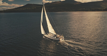 Sailboat at mountain island aerial. Nobody nature seascape. Luxury yacht sailing at open sea. Business cruise at Atlantic ocean bay. Yachting sport. Cross from Caribbean to Europe. Dramatic drone shot