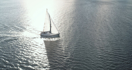Sun seascape with alone sail boat aerial. Luxury yacht at open sea racing under sails. Majestic...