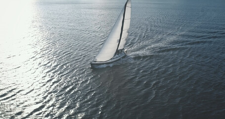Sun reflection at closeup luxury yacht on ocean bay aerial. Wind white sails at passenger boat....