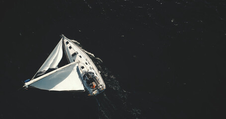 Top down of white sailing yacht on black water of ocean bay aerial. Nobody nature seascape at...