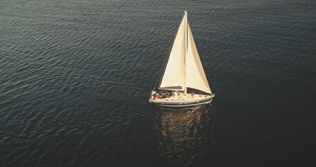 Aerial sun light above sea surface with sail boat. Yacht cruising at serene waterfront. Summer...