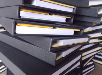 chaotic stack of thick diaries with black hard covers in a printing industry warehouse