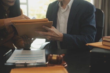 Justice and Law concept. Legal counsel presents to the client a signed contract with gavel and legal law or legal having team meeting at law firm in background - obrazy, fototapety, plakaty