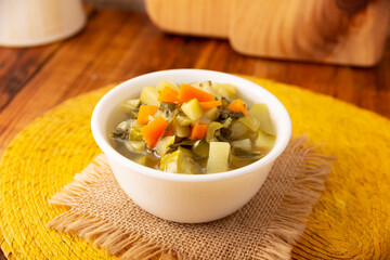 Homemade fresh vegetable soup, easy recipe made with chopped vegetables, carrot, celery, pumpkin, spinach, chayote and other ingredients, healthy dish popular in many countries.