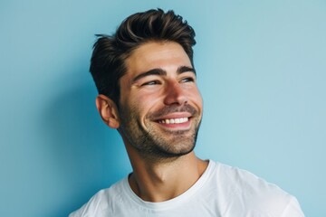 Portrait of a happy young man smiling on a blue background.