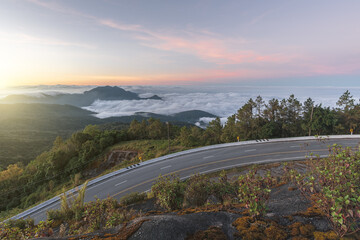 Long curvy forest asphalt road over the hills. Beautiful curved road in the forest. Side view of road with fog at sunrise. - 782707914