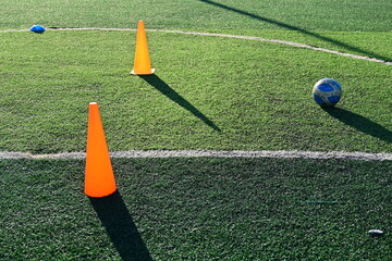 artificial green grass soccer field with orange training cones - 782725124