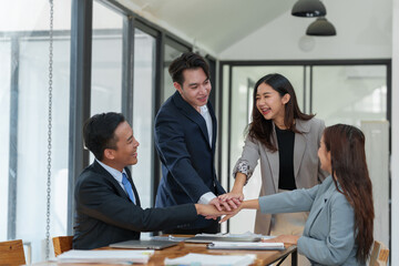 Smiling Asian businessman raising his hands Clapping happily at the table in the office Group of successful Asian business teams discuss cooperation Presentation and analysis of successful reports.