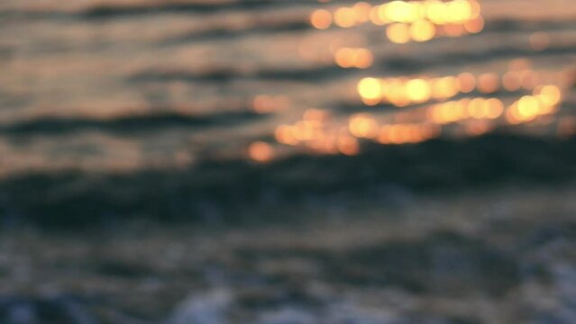 A summer ocean sunset sea background with small waves on the water's surface in lights from sunrise