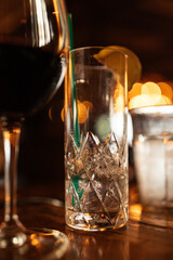drink ware on table at restaurant at night: wine, tall crystal glass with straw and citrus, water glass