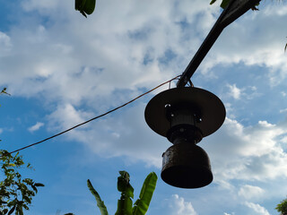 an antique lamp, a strongking lamp hanging in a banana garden with a cloudy blue lamp as a...