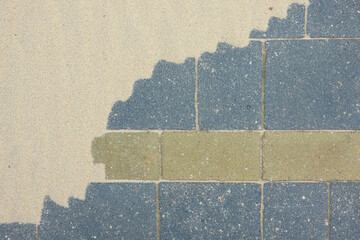 A fragment of a pavement made of gray and green paving slabs is partially covered with sand....