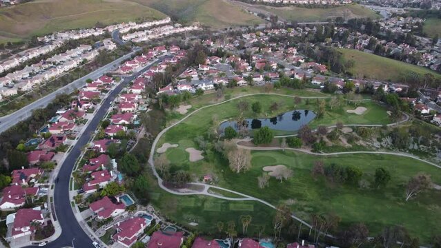 Aerial shot of Simi Valley, CA lake and park in the middle of homes, panning up to the horizon and mountains