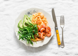 Delicious breakfast, brunch - omelette with shrimp, arugula and avocado on a light background, top view