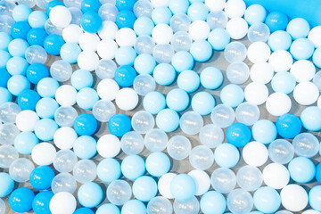 Colored plastic balls in pool of kindergarten school,White and blue plastic balls pit in game room,Many white balls background.