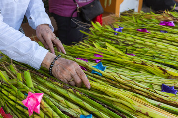 A laywoman arranges green palm fronds with ribbon accents to be sold during Palm Sunday...