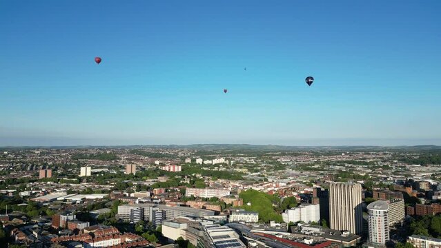 Aerial shot of Bristol with four hot air balloons flying above it.