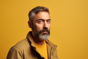Fototapeta premium A man with a beard and gray hair is wearing a yellow jacket