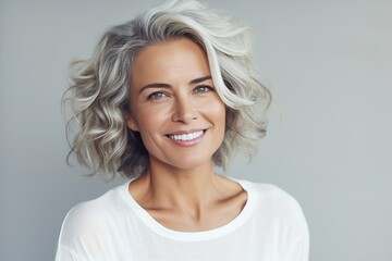 Fototapeta premium A woman with short gray hair and a white shirt is smiling