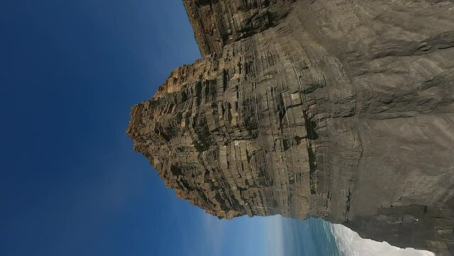 Vertical FPV: Flight up rugged rock strata sea stack, Portugal coast