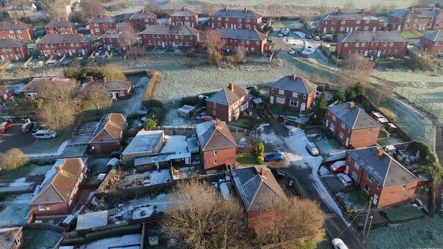 Drone's-eye winter view captures Dewsbury Moore Council estate's typical UK urban council-owned housing development with red-brick terraced homes and the industrial Yorkshire. Working class housing