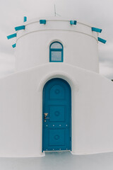 A blue door with a lock sits in front of a white building. The door is the only visible part of the building, and it is blue in color.
