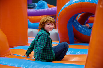 Cute boy playing on inflatable bounce house in entertainment center - 782819520