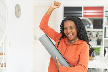 Portrait of successful cheering black woman with yoga mat