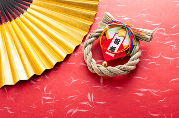 金色の扇と正月飾りと赤色の和紙の和風イメージ　