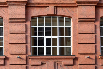 A large window with white frames on a brown brick facade