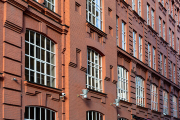Facade of old classic red brick building with large windows with white frames