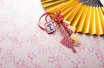 金色の扇と正月飾りとピンク色の和紙の和風イメージ