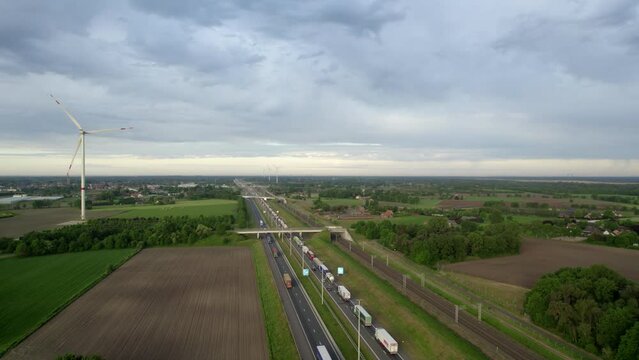 This aerial footage provides a sweeping view of the E19 highway as it carves through the green landscapes of Brecht, juxtaposed with the sustainable energy of wind turbines. The dynamic interaction