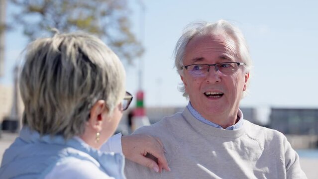 Senior man talking with his wife outdoors. Mature happy couple having conversation.