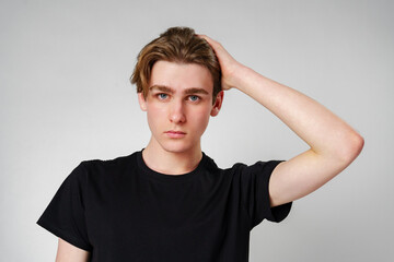 Young Man With Hand in Hair Posing Against a Light Grey Background