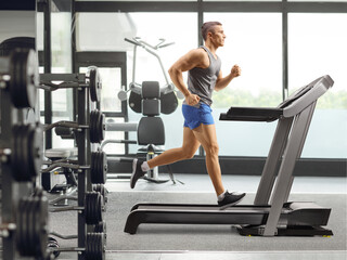 Fit young man running on a treadmill at a the gym