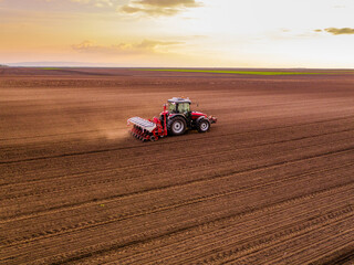 Aerial shot of a farmer seeding, sowing crops at field. Sowing is the process of planting seeds in the ground as part of the early spring time agricultural activities.