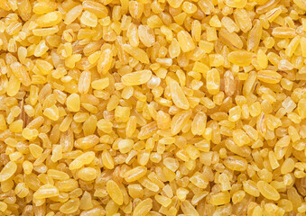 Yellow raw organic healthy bulgur grain seeds textured background.Macro.