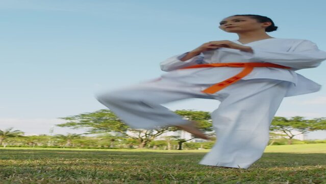 Vertical shot of female athlete in white taekwondo uniform training on open air alone