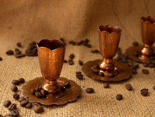 copper cups and coffee beans placed on a sack material background