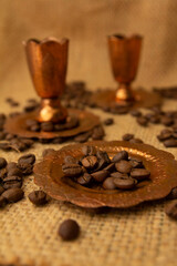 copper cups and coffee beans placed on a sack material background