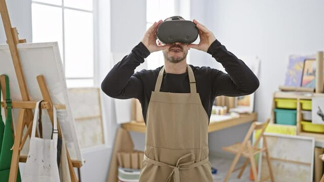 A bearded man wearing a vr headset and apron gestures in a bright art studio, showcasing technology in a creative space.