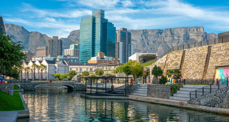 A canal in the marina district of Cape Town, with the city center skyline and Table mountain in the...