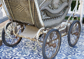 Old retro slightly dirty and rusty four-wheeled stroller