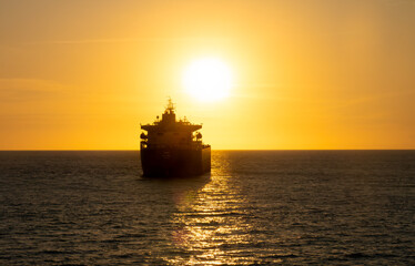 The silhoette of a container ship during an equinox sunset in Luanda, Angola, Central Africa