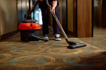 Close up of hotel maid vacuuming  hallway.