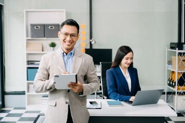 Young attractive Asian male office worker business suits smiling at camera in office