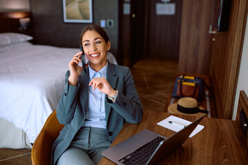 Happy businesswoman making  phone call in hotel room.