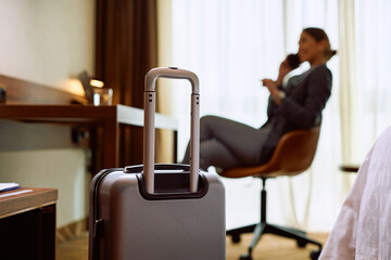 Close up of suitcase in hotel room with businesswoman in  background.