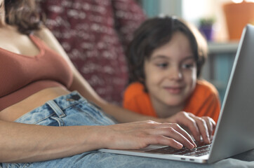 a woman with a child is sitting at a laptop - 782863507